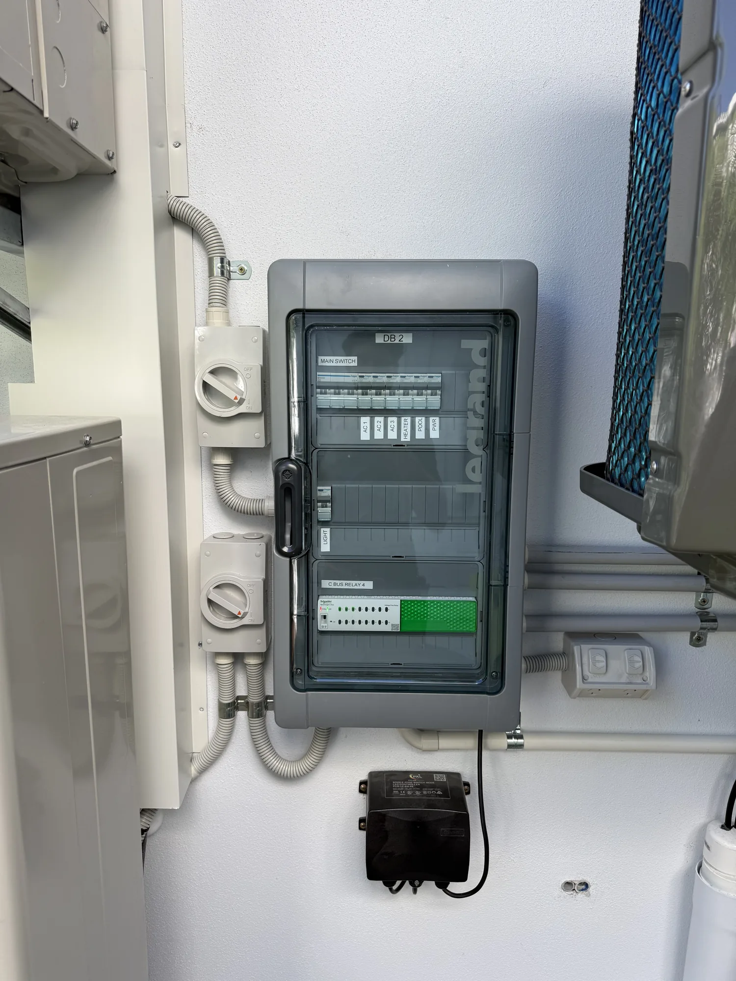 Weatherproof distribution board with labelled air-conditioning, pool and lighting circuits and a C-Bus automation relay, installed by Wire & Watt, Brisbane