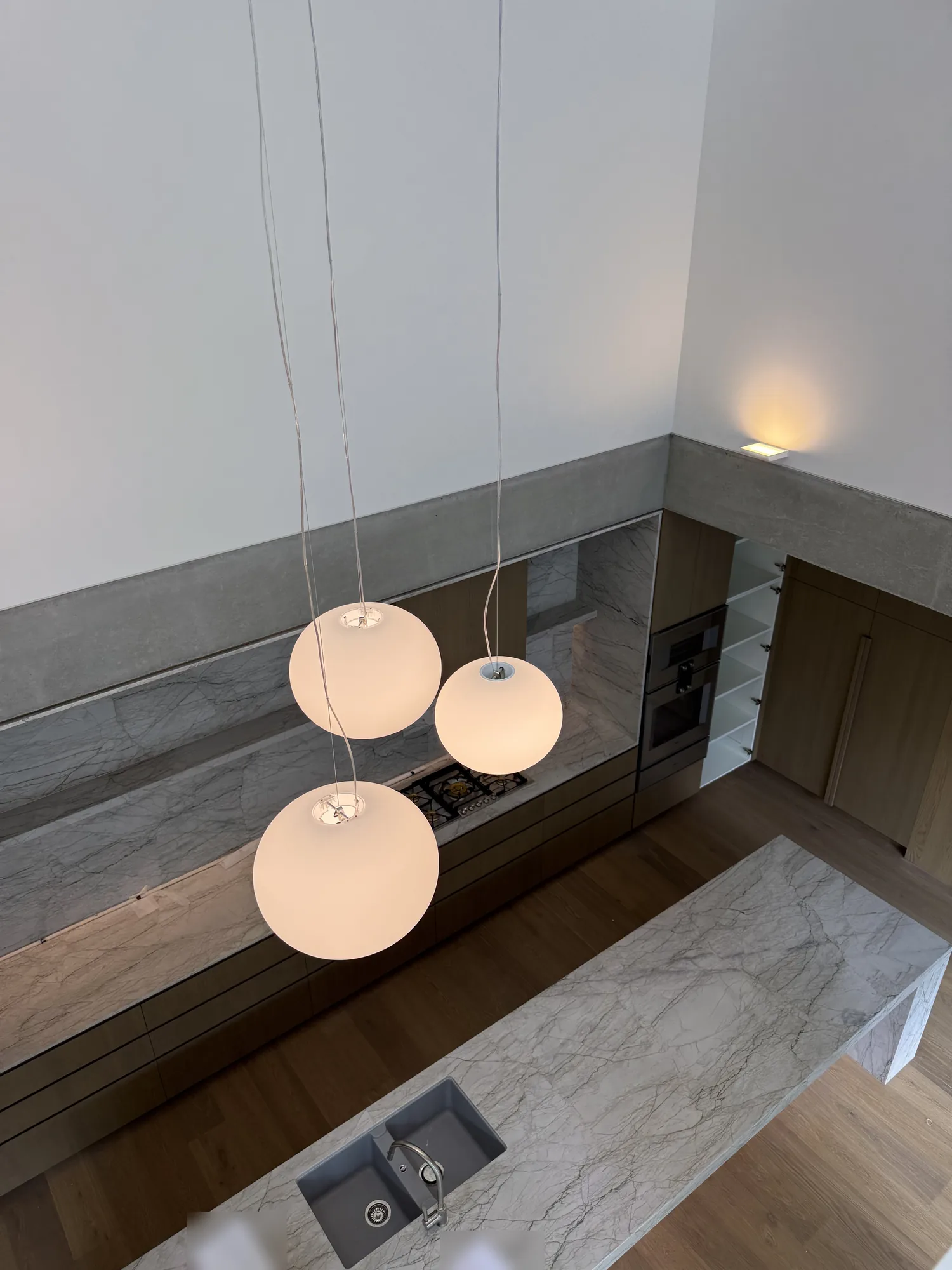 Pendant light installation over a marble kitchen island in a Brisbane home by Wire & Watt
