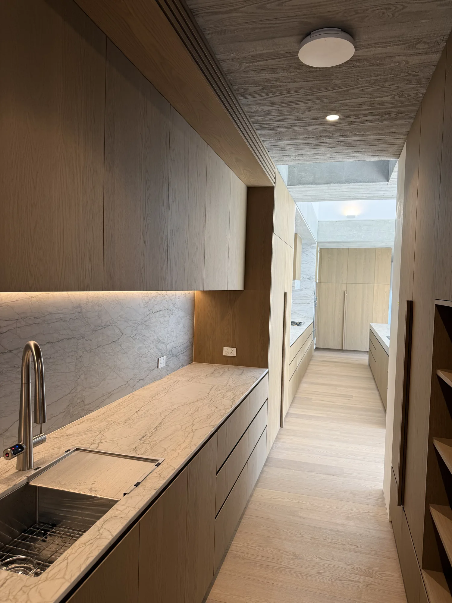 Butler's pantry and scullery with marble benchtops and under-cabinet lighting by Wire & Watt, Brisbane
