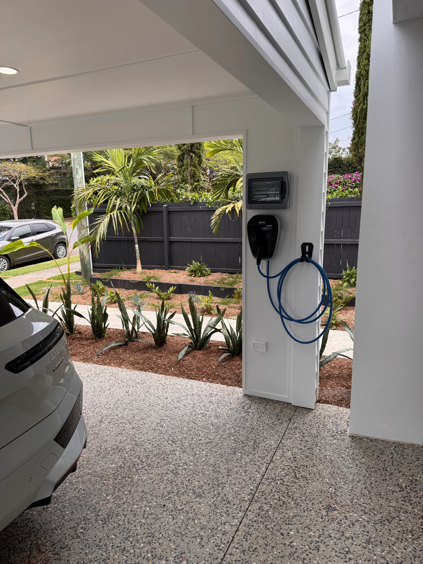 BMW electric vehicle charger installed in a residential carport beside a parked vehicle
