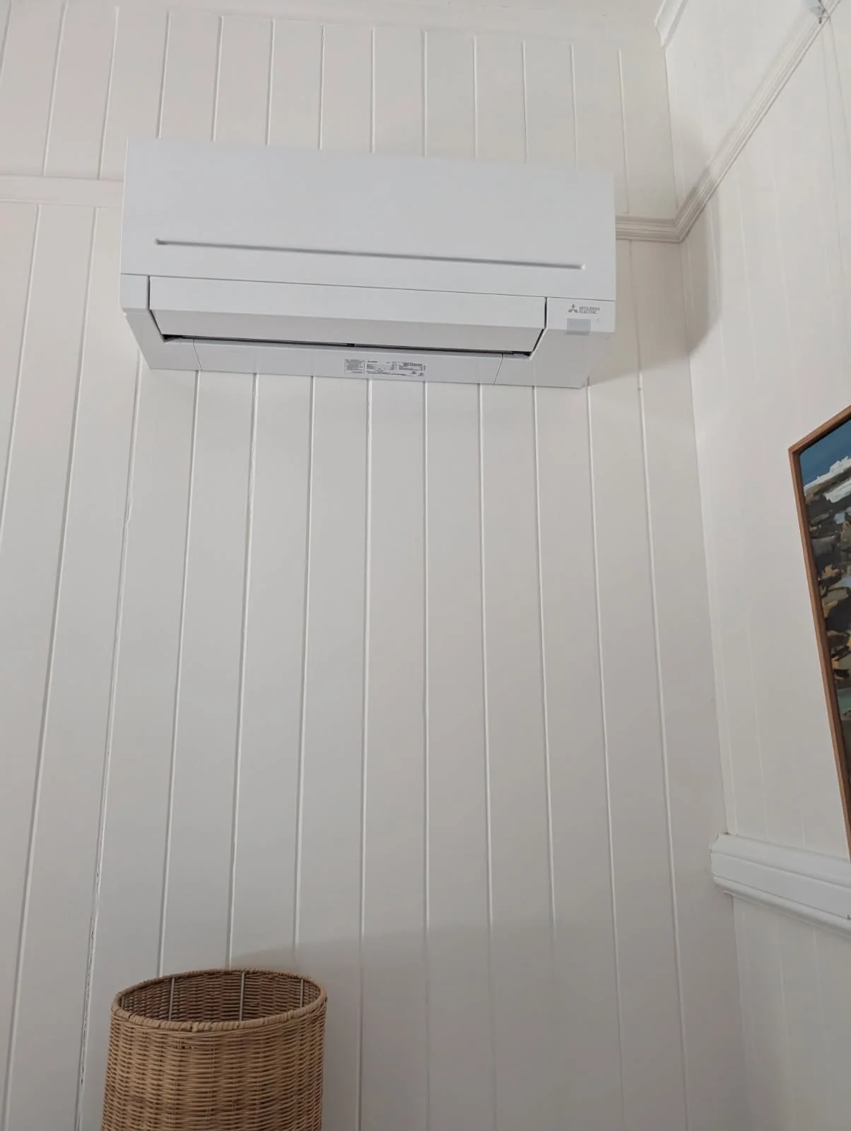 Mitsubishi Electric split-system air conditioner mounted high on a white VJ wall